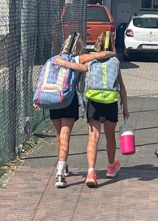Young JTA players sharing a moment beside the tennis courts
